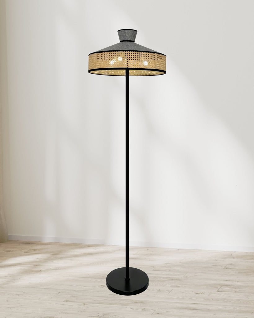 Cane floor lamp with rattan weave shade and black metal stand, styled in a minimalist setting with soft window light.