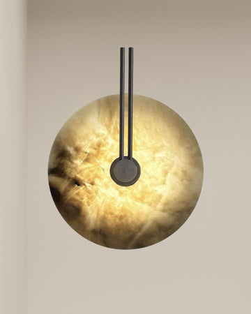 Circular alabaster wall sconce with warm backlit glow and black double-rod arm mounted on beige wall