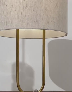 Close-up video of the Arden Table Lamp showing the curved brass frame and textured white fabric shade against a white wall, highlighting its elegant and modern design.