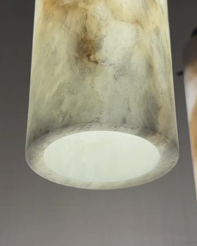 Close-up video of illuminated vertical alabaster pendant light with brass fixture, highlighting natural stone patterns.